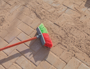 Sweeping sand at a construction site. A construction worker brushes dry sand into the seams of paving stones during road work.