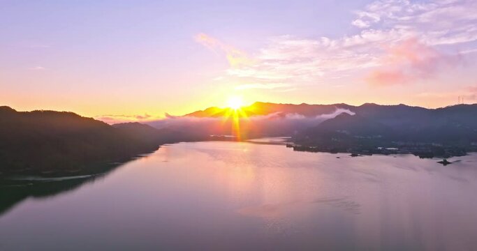 Aerial video of beautiful lake and mountain with sun natural landscape at sunrise in Hangzhou. Drone ascending to shoot.