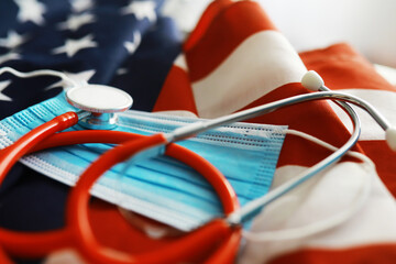 American health care system. USA flag background. Medical mask and restrictions.