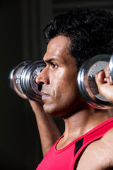 Athletic Indian man exercising with dumbbells