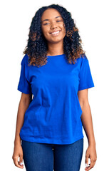 Young african american woman wearing casual clothes looking positive and happy standing and smiling...