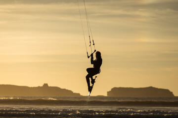 Silhouette of kitesurfer on the beach with reflection at sunset in background. Essaouira, Morocco - obrazy, fototapety, plakaty
