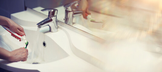 Tooth brush and paste with mirror background in the bathroom. Close up of toothpaste and toothbrush. Hands squeezing whitening paste on brush, taking care about mouth hygiene.