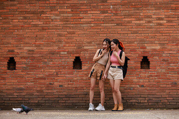 two asian tourist girl standing looking pigeons at the tha phae gate, chiang mai thailand,