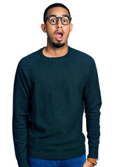 Fototapeta premium Young african american man wearing casual clothes and glasses afraid and shocked with surprise expression, fear and excited face.