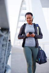 Woman listening to the music and using smart phone while going for morning workout