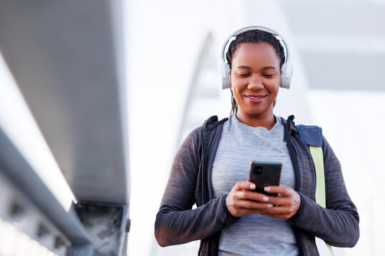 Woman using smart phone and listening to the music while going for morning workout