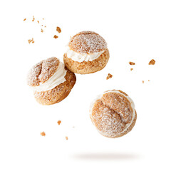 Cream puffs, pastry from choux covered sugar powder with crumbs falling flying isolated on white...
