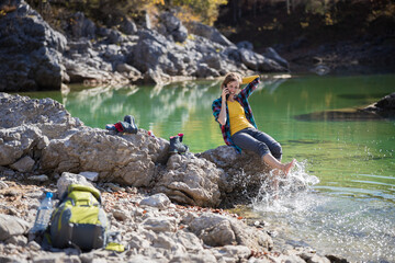 Mid Adult Woman Talking on a Phone on a Break from Hike Splashing Barefoot in Alpine Lake