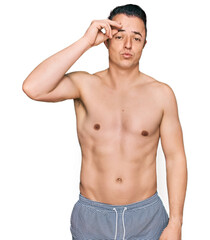 Fototapeta premium Handsome young man wearing swimwear shirtless worried and stressed about a problem with hand on forehead, nervous and anxious for crisis