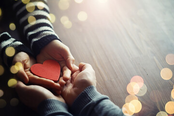 Woman holding hands with red heart on wooden background, top view