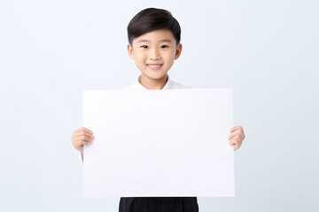 Happy Asian Scholl boy holding blank white banner sign, isolated studio portrait .