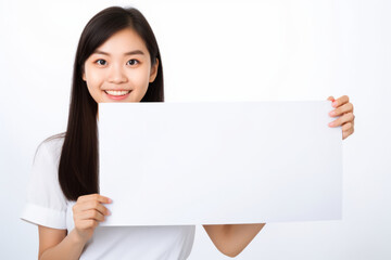 Naklejka premium Happy asian scholl girl holding blank white banner sign, isolated studio portrait.