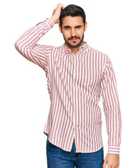 Young hispanic man wearing business shirt confuse and wonder about question. uncertain with doubt, thinking with hand on head. pensive concept.