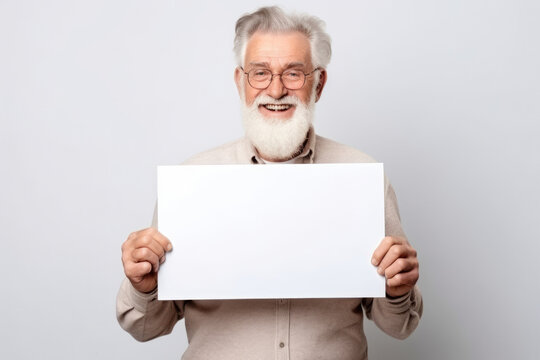 Happy old man holding blank white banner sign, isolated studio portrait.