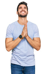 Young hispanic man wearing casual clothes begging and praying with hands together with hope...