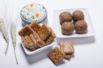 Indian traditional sweets sesame and jaggery laddu bite and hcolourful halwa on white background 