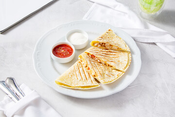 Quesadilla with cheese and chicken, with red and white sauce on a plate