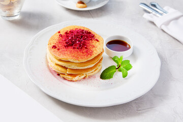 Fototapeta na wymiar Fluffy pancakes with maple syrup and raspberry powder