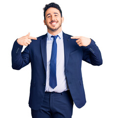 Young hispanic man wearing business clothes looking confident with smile on face, pointing oneself...