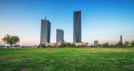 Fototapeta na wymiar Green Urban Park Against City Skyline at Dusk