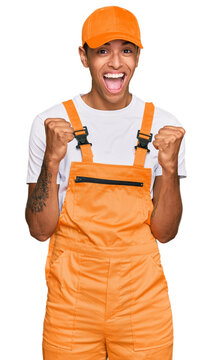 Young handsome african american man wearing handyman uniform celebrating surprised and amazed for success with arms raised and open eyes. winner concept.