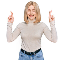 Fototapeta na wymiar Young blonde woman wearing casual clothes gesturing finger crossed smiling with hope and eyes closed. luck and superstitious concept.