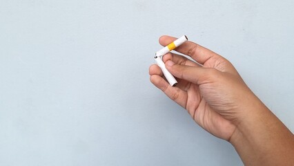 Hand holding a broken cigarette. No smoking concept. Isolated in gray background.