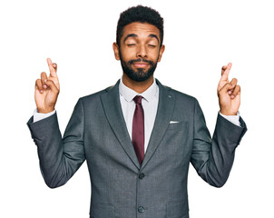 Young african american man wearing business clothes gesturing finger crossed smiling with hope and eyes closed. luck and superstitious concept.