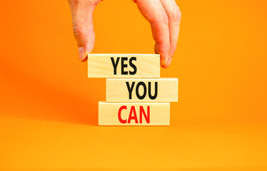 Motivational and Yes you can symbol. Concept words Yes you can on beautiful wooden blocks. Beautiful orange background. Businessman hand. Business motivational and Yes you can concept. Copy space.