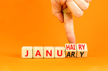 Januhairy or January symbol. Concept words Januhairy or January on beautiful wooden blocks. Beautiful orange table orange background. Man hand. Social issues Januhairy or January concept. Copy space.