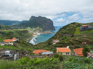 Obraz premium Aerial view of Porto da Cruz town with green cliff of Penha D'Aguia mountain and beautiful coast. Landscape scenery at the north of Madeira island, Portugal