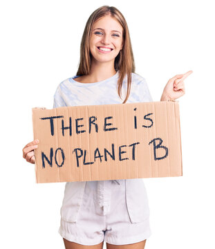 Young beautiful blonde woman holding there is no planet b banner smiling happy pointing with hand and finger to the side