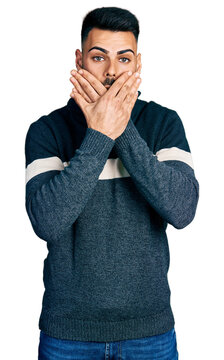 Young hispanic man with beard wearing casual winter sweater shocked covering mouth with hands for mistake. secret concept.