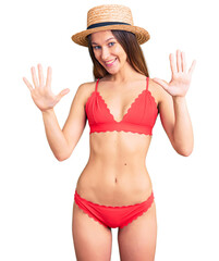 Beautiful brunette young woman wearing bikini showing and pointing up with fingers number ten while smiling confident and happy.
