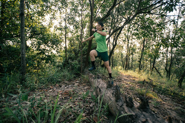 Naklejka na ściany i meble Woman trail runner running at tropical forest mountain peak