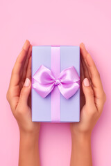 A woman's hands are holding a purple gift box with a bow.