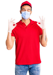 Young handsome hispanic man wearing delivery uniform and medical mask relax and smiling with eyes closed doing meditation gesture with fingers. yoga concept.