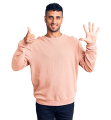 Young hispanic man wearing casual clothes showing and pointing up with fingers number six while smiling confident and happy.