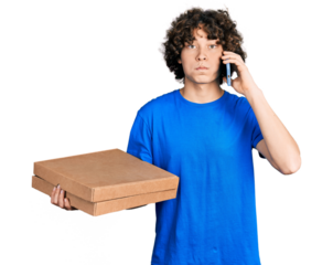 Caucasian teenager holding delivery package and talking by the smartphone puffing cheeks with funny face. mouth inflated with air, catching air.