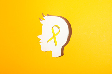 A child's head made of white paper with a yellow ribbon