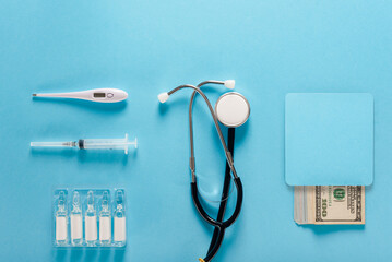 thermometer stethoscope and ampoules lying near dollars money showing corruption in medicine concept