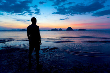 Lonely Asian middle edge man standing on the beach watching sunset sky in the evening. Back of...