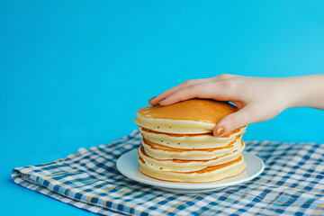 Food pop art photography. Female hand and sweet pancakes on plaid tablecloth isolated on bright...
