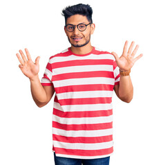 Naklejka premium Handsome latin american young man wearing casual clothes and glasses showing and pointing up with fingers number nine while smiling confident and happy.