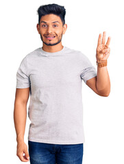 Handsome latin american young man wearing casual tshirt showing and pointing up with fingers number three while smiling confident and happy.
