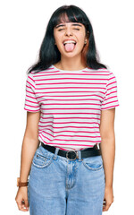 Obraz premium Young hispanic girl wearing casual clothes sticking tongue out happy with funny expression. emotion concept.