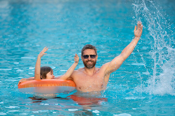 Father and son swimming in pool, summer family weekeng. Father and son splash water in pool on summer family holiday. Dad and child relaxing in pool water. Child with dad swimming in pool.