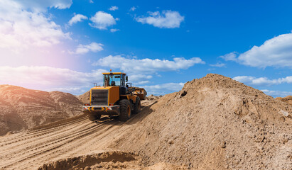 Yellow excavator unloading sand on Open pit mine quarry, sunlight. Concept industrial banner, heavy...