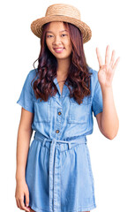 Obraz na płótnie Canvas Young beautiful chinese girl wearing summer hat showing and pointing up with fingers number four while smiling confident and happy.